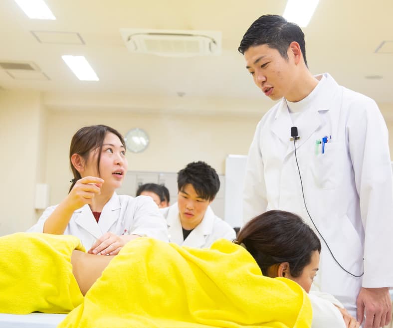 教員の指導のもとで治療実習に取り組む学生たちの様子