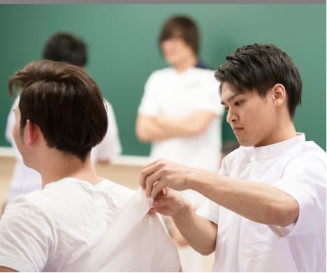 白衣を着た学生が実習で手技の練習をしている様子