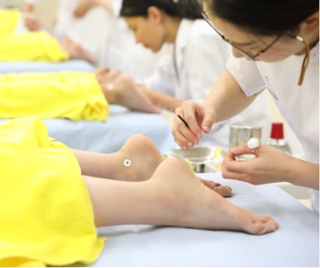 鍼灸実技で足に施術を行う学生の様子