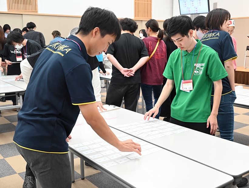 要穴カルタ大会で札を取り合う学生たちの様子。集中して取り組む姿が印象的。