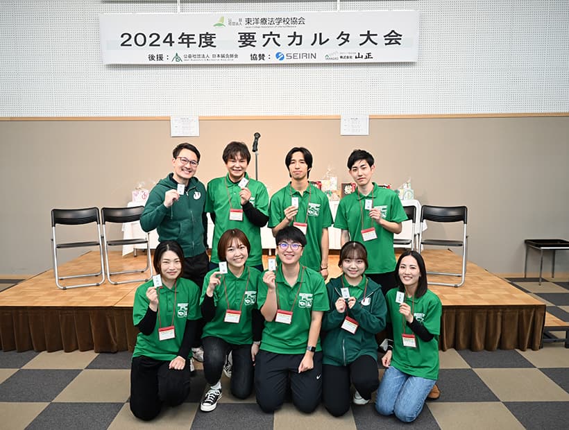 2024年度 要穴カルタ大会に参加した学生たちの集合写真。緑のユニフォーム姿で記念撮影。
