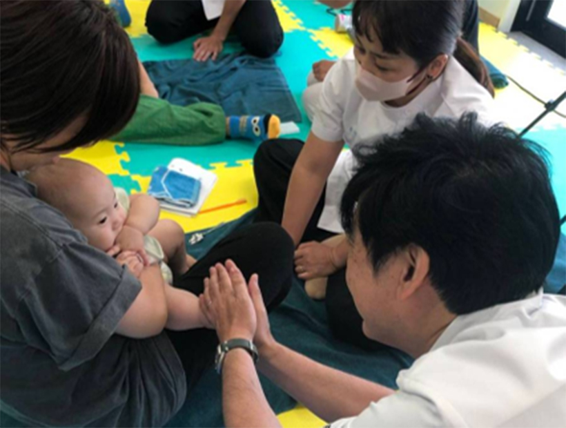 乳児を抱える保護者と向き合いながら、保健指導を行う様子