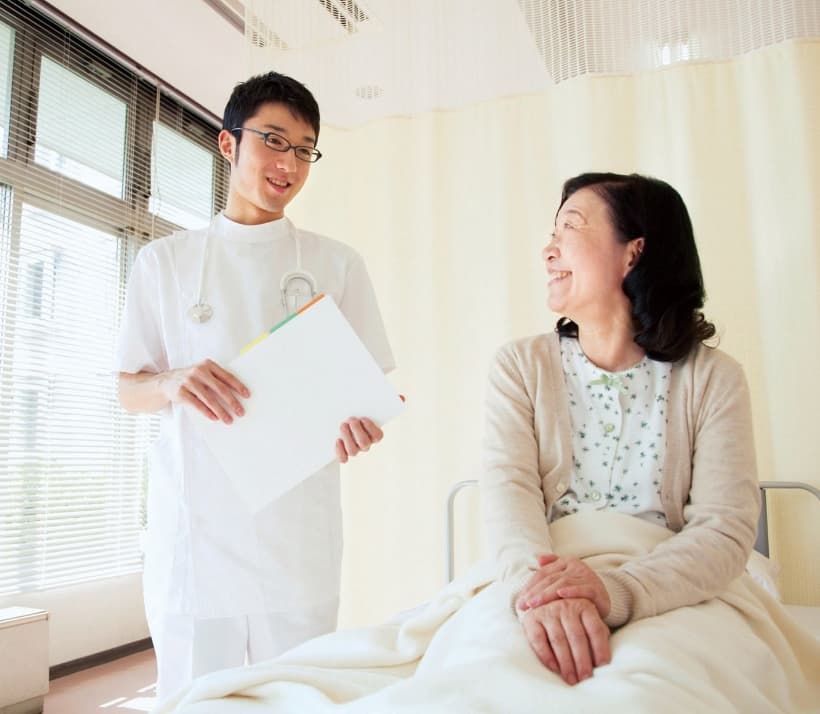 柔道整復師が病院で患者と笑顔で会話する様子