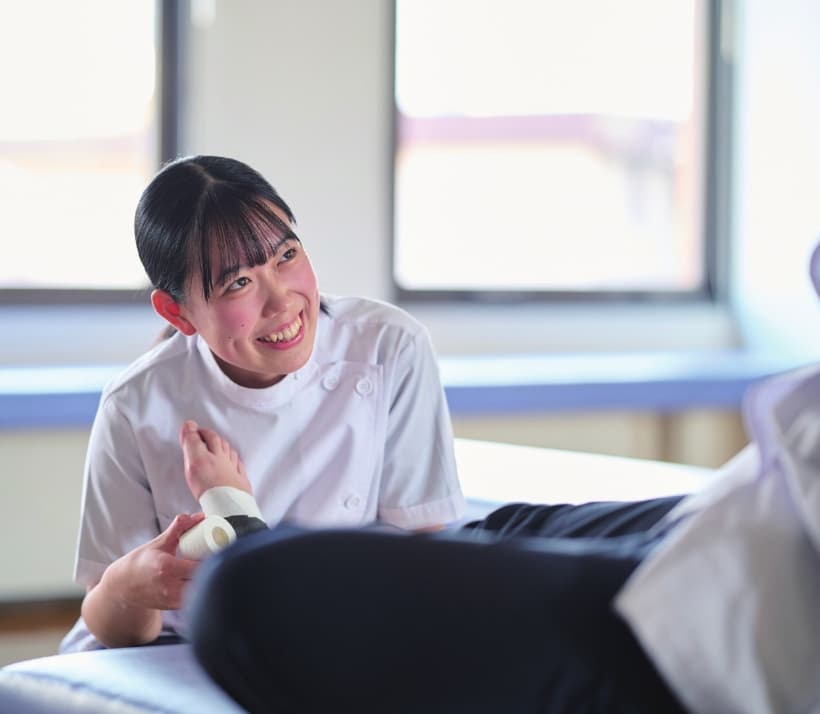 柔道整復師を目指す学生が実習で患者にテーピングを行っている様子