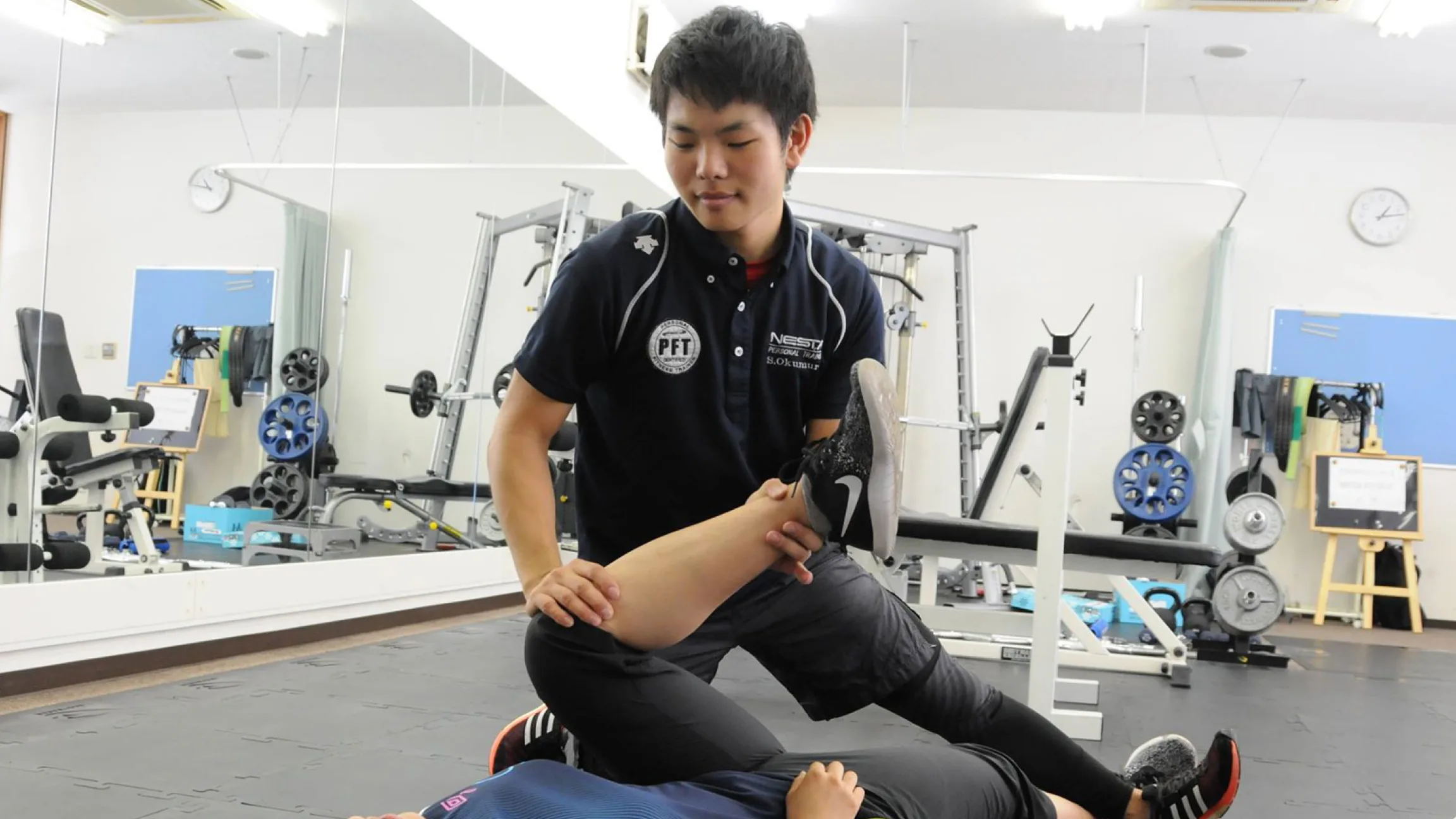 トレーニングルームでストレッチを指導するNESTA PFT資格を持つトレーナー