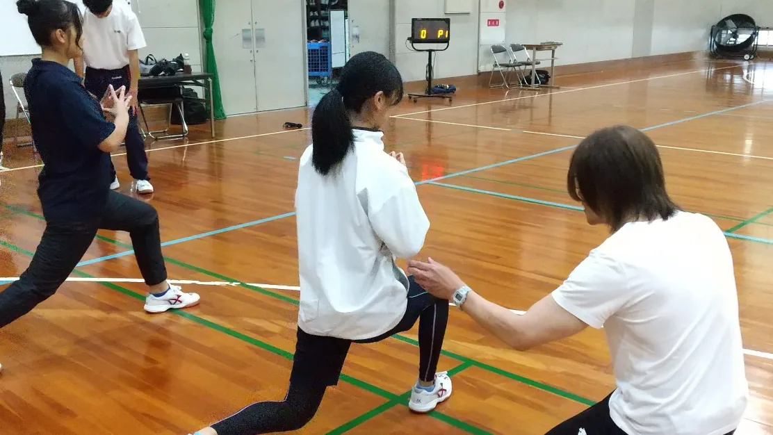 体育館で高校生にストレッチを指導する様子