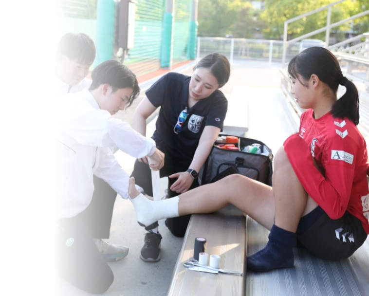 INAC神戸レオネッサの選手にテーピングをする学生